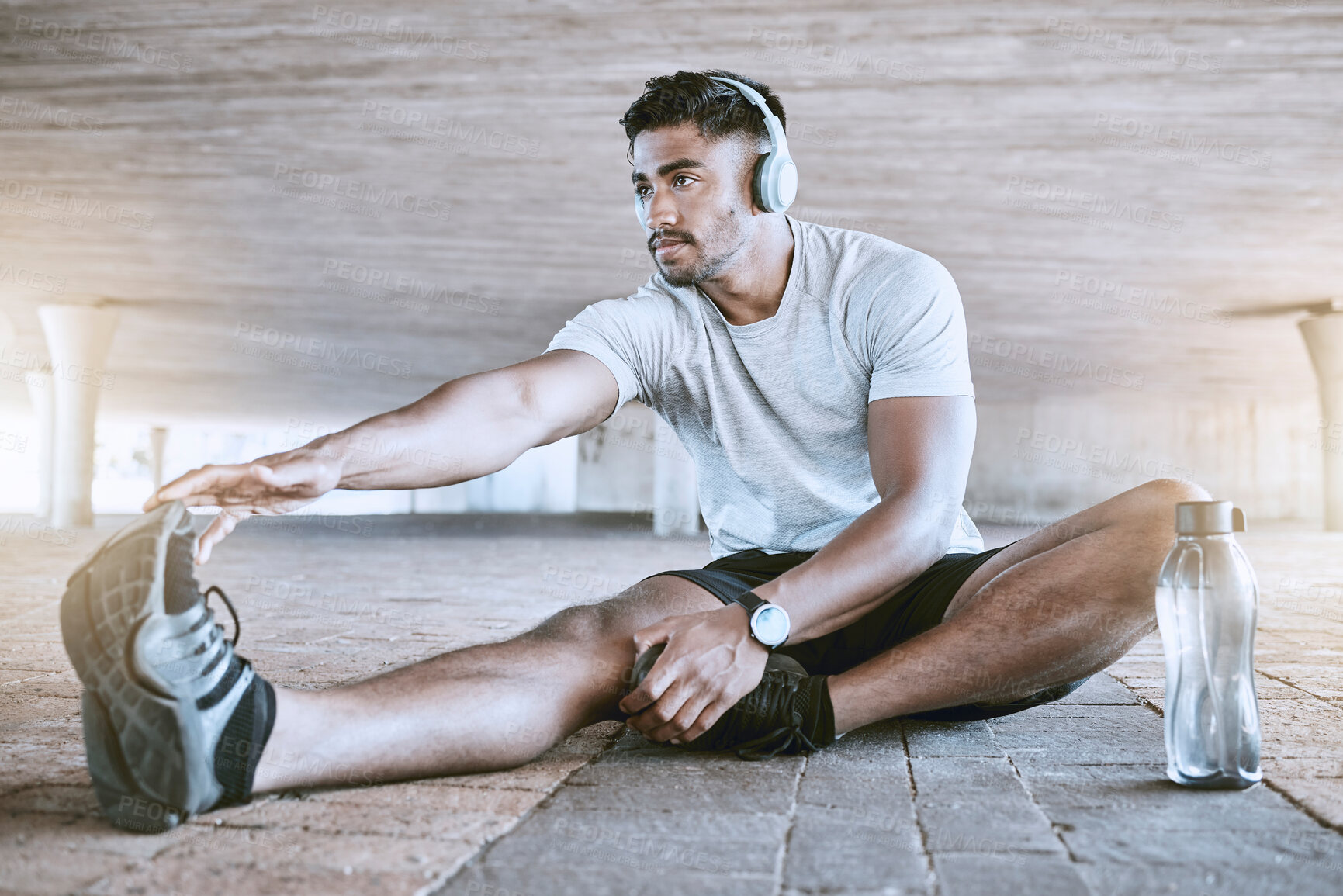 Buy stock photo Sports, training and running stretching of a fitness trainer or runner about to start a workout. Running man athlete with headphones ready to improve health, wellness and performance with a exercise