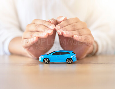 Buy stock photo Care insurance, security and safety with the hands of a broker covering model or toy transport on a table in a corporate office. Finance, accountant and travel with an employee offering vehicle cover