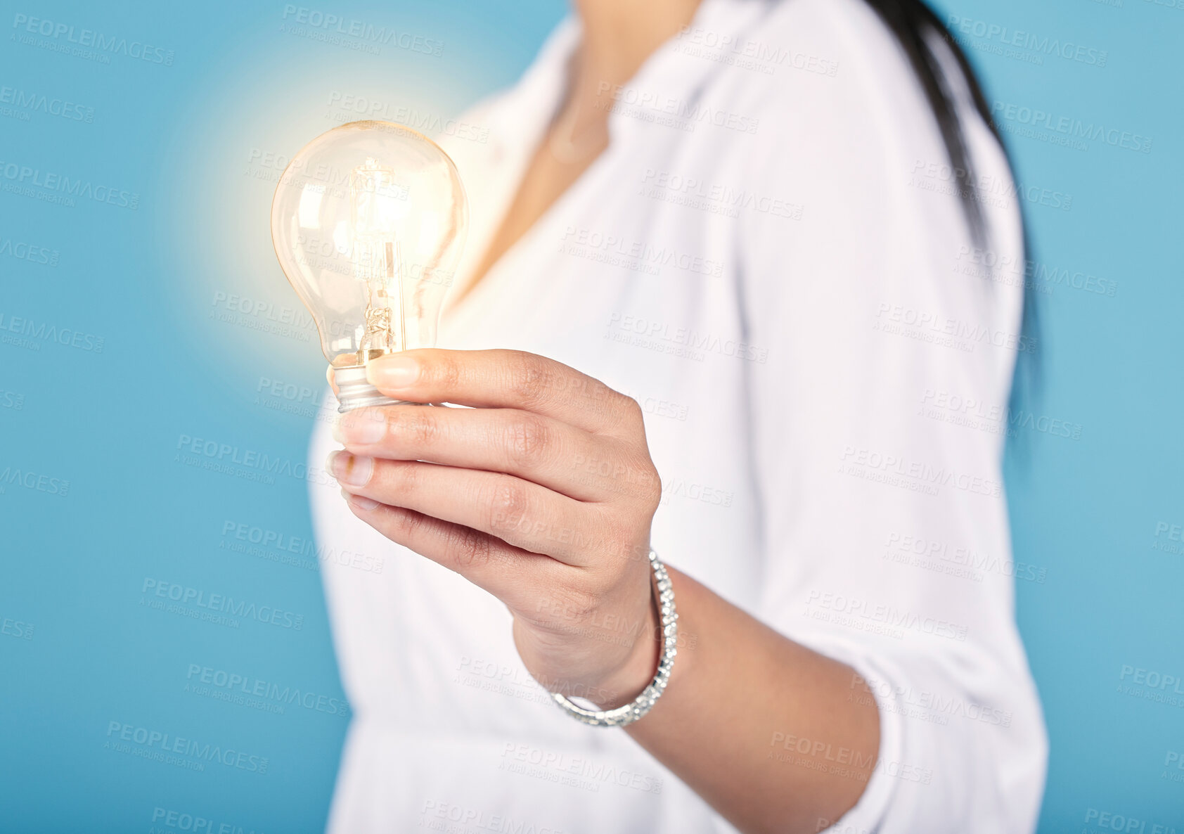 Buy stock photo Lightbulb moment, idea and creativity with a light in the hand of a woman in studio isolated on a blue background. Closeup of motivation, innovation and development in energy, power and electricity