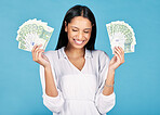 Money, winner and cash in hands of a woman cheering wealth and success in celebration with a wow in studio on blue background. Rich, celebrating and excitement with a happy female winning the lottery