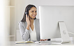 Call center agent talking or consulting online clients with a headset and working on a desktop computer in a company office. black woman customer support worker helping people with questions