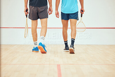 Buy stock photo Rear view of two unknown squash players walking together on court and holding rackets before game. Fit active mixed race and caucasian athlete getting ready for training and practice in sports centre