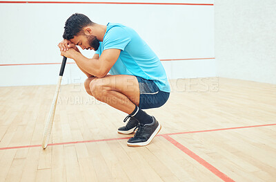Buy stock photo One unknown athletic squash player crouching and feeling sad and stressed after playing game on court. Fit active mixed race athlete feeling anxious after mistake in training practice in sports centre