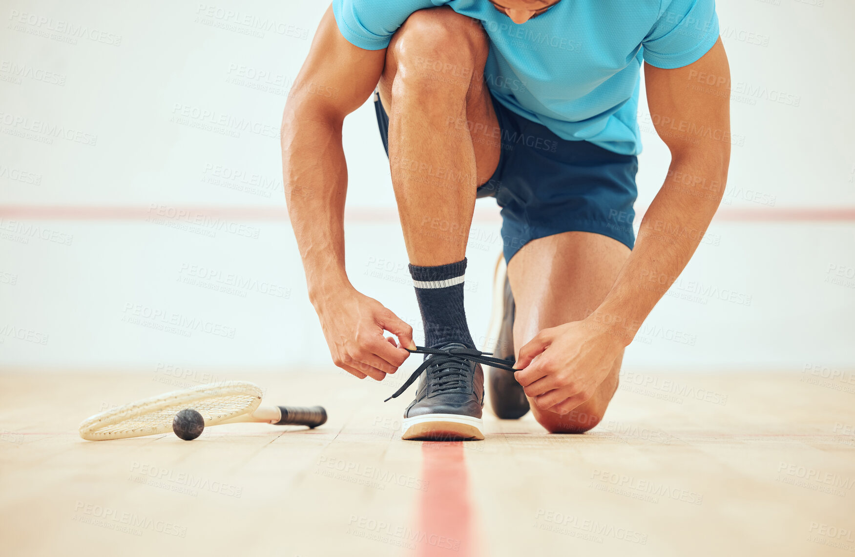 Buy stock photo Unknown athletic squash player kneeling and tying shoelaces before playing court game with copyspace. Fit active mixed race athlete getting ready for training practice at sport centre. Sporty hispanic