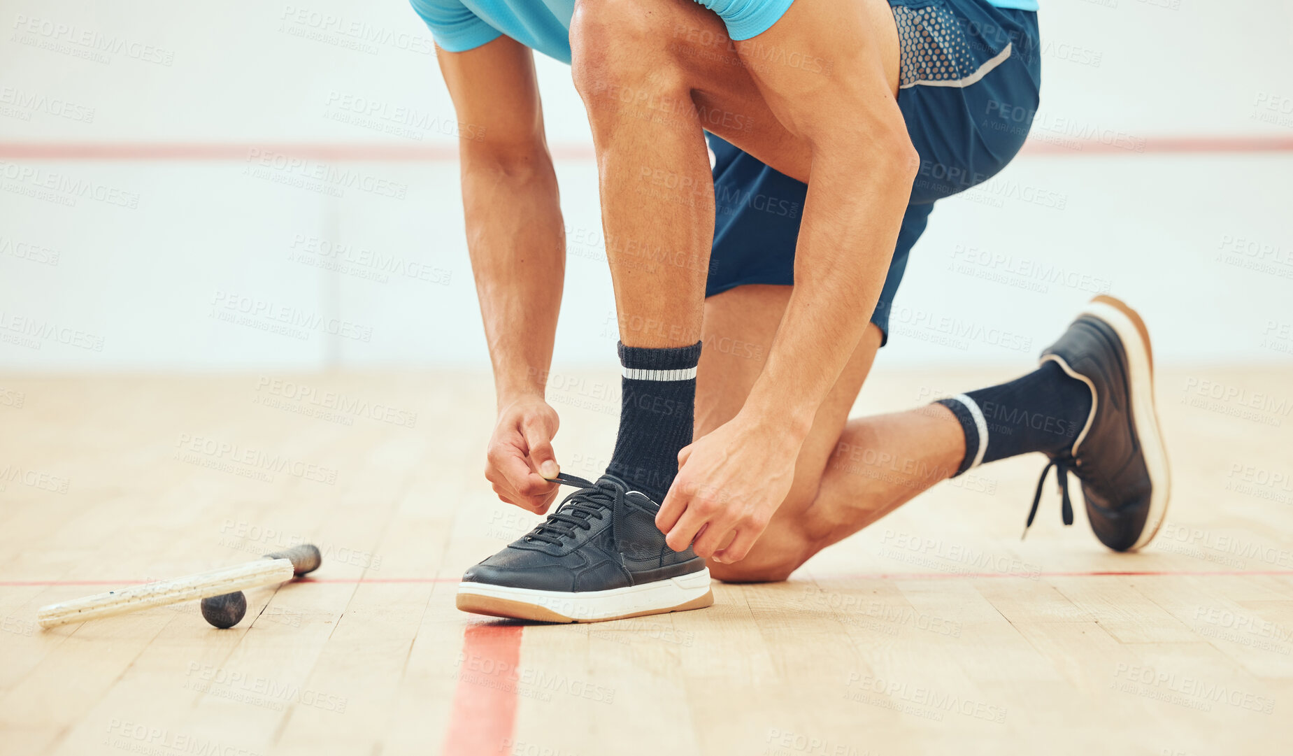 Buy stock photo Unknown athletic squash player kneeling and tying shoelaces before playing court game. Fit active mixed race athlete crouching and getting ready for training practice at sport centre. Sporty hispanic