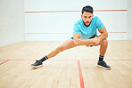 Full length of squash player stretching and looking focused before playing court game with copyspace. Fit active hispanic athlete standing alone and getting ready for training practice in sports centre