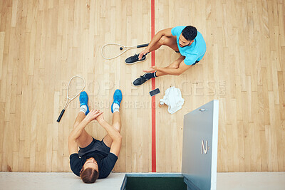Buy stock photo Above view of two unknown athletic squash players sitting together after playing court game. Fit active mixed race and caucasian athletes resting after training practice in sports centre. Sporty men