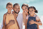 Family of four smile are at the beach are happy out in the sun while they spend quality time together. Dad and mom hug kids, they bond and have fun on summer vacation in portrait. 