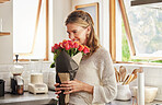 Flowers, smile, and elderly woman smelling rose in a kitchen, surprised by sweet gesture and or secret gift. Happy, romantic and kind surprise for mature, excited woman on valentines morning