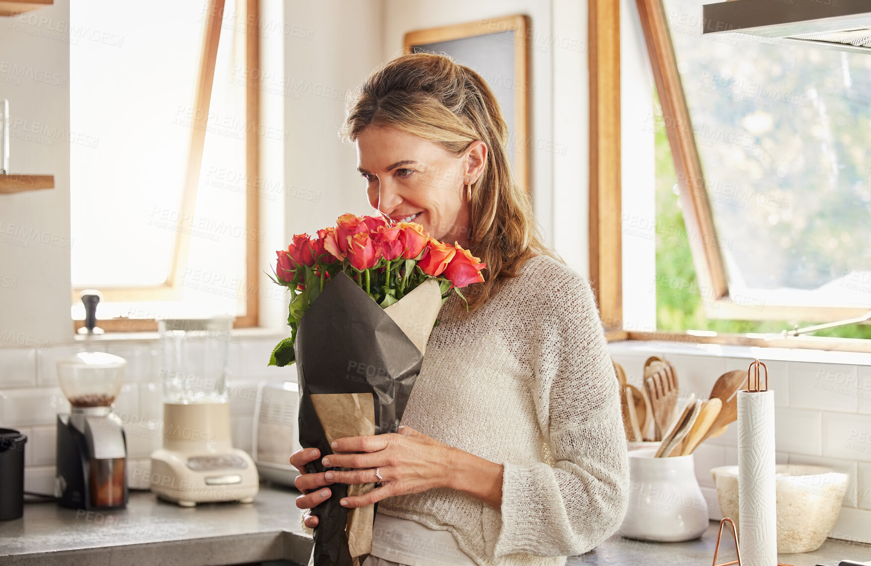 Buy stock photo Flowers, smile, and elderly woman smelling rose in a kitchen, surprised by sweet gesture and or secret gift. Happy, romantic and kind surprise for mature, excited woman on valentines morning