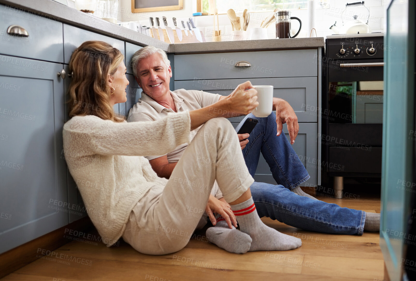 Buy stock photo Senior couple, morning coffee or bonding on kitchen floor in house or Canada home in trust, love or security. Smile, happy or talking retirement elderly man or mature woman with tea or life insurance