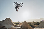Mountain bike jump training man on rocks hill cycling in air, blue sky mockup for professional performance, training or outdoor bike exercise. Sports person on outdoor motorcycle or bicycle adventure
