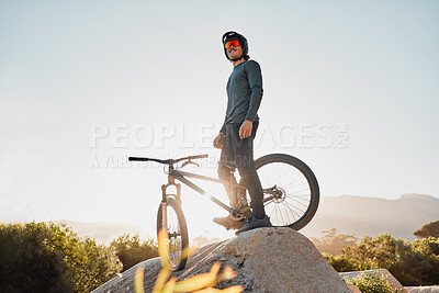 Buy stock photo Mountain bike or motorcycle cyclist on rock for marathon goal, sports adventure or outdoor travel with sunglasses and helmet. Fitness training man with bicycle on a hill blue sky mockup in Australia