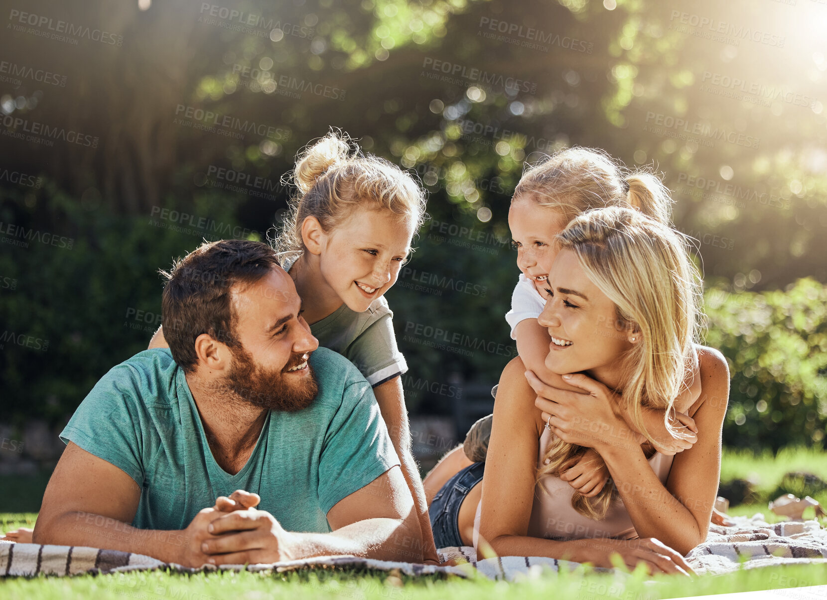 Buy stock photo Picnic park and family with children relax on grass together for outdoor bonding, love and care with sunshine summer lens flare and trees. Nature, healthy and support parents with girl kids on ground