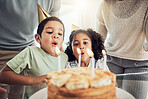 Children, birthday cake and blowing candles in celebration event, fun party or Brazilian family social reunion with parents. Boy, girl or kids with sweet dessert food in house or home with mom or dad