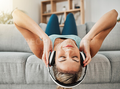 Buy stock photo Relax, music and freedom with a woman listening to audio on headphones while lying on a sofa in the living room of her home. Wellness, mental health and streaming with a young female alone in a house