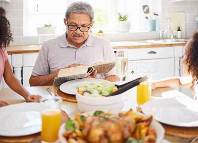 Buy stock photo Food, family and books with grandfather reading to children at a table, bonding and storytelling before sharing a meal. Bible, religion and senior man teaching grandkids faith and scripture in home