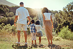 Family, walk and nature together with trees, grass and sunshine while on vacation. Mom, dad and children walking in forest, field or park in spring for beauty of plants in countryside, woods or wild