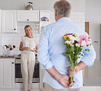 Elderly, couple and flowers in kitchen for surprise, love and romance in their house. Woman, man and retirement together with bouquet to celebrate marriage, birthday or anniversary in their home