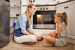 Cooking, mom and child on kitchen floor in house talk and relax while waiting for food in the oven. Canada mother enjoying happy food preparation leisure break with young daughter in family home.
