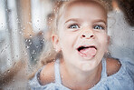 Funny, kid and tongue on window portrait with goofy and enthusiastic face pressed on surface. Young, happy and crazy girl child enjoying playful lick on glass with rain droplets closeup.

