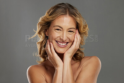 Buy stock photo Portrait of a happy smile, beauty and skincare mature woman looking positive and cheerful while caring for her skin. Face, skincare and cosmetic female face in a studio against grey mockup background