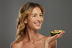 Woman, happy and avocado in hand for health, wellness and detox care with face. Mature model, dermatology and smile with fruit diet for skincare, hair and beauty with natural facial cosmetic product