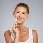 Portrait of a woman with facial cleanser, skincare and beauty products. Young girl with natural beauty, happy and healthy skin smiling while cleaning her face with cotton wipe using skincare products