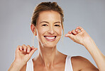 Smile, teeth and dental of a woman floss, beauty and healthcare in a grey studio background. Portrait of happy mature female cleaning for healthy mouth care, tooth and gum hygiene with a clean tooth