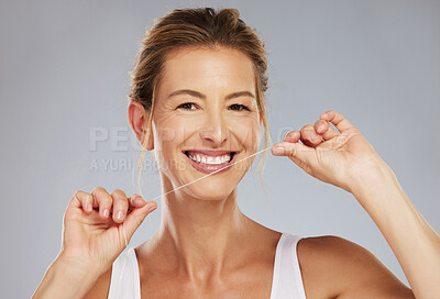 Buy stock photo Smile, teeth and dental of a woman floss, beauty and healthcare in a grey studio background. Portrait of happy mature female cleaning for healthy mouth care, tooth and gum hygiene with a clean tooth