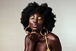 Black woman, beauty and retro fashion, afro hair and blow air kiss with gold makeup and jewelry on studio background. Portrait, gesture and face of female cosmetics model from Jamaica flirting inside