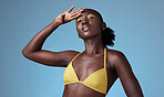 Black beauty, yellow bikini and an African woman on blue background, a queen in yellow. Bright makeup, dark skin and a beautiful girl. Skincare, colorful cosmetics and a portrait of lady from Africa.