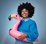 Portrait of woman in blue with a flamingo and a smile on her face. Happy young black woman with a rubber ring on waist on blue background. Mockup for trendy, travel and fun for summer vacation