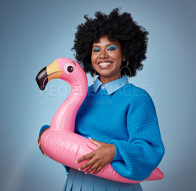 Buy stock photo Portrait of woman in blue with a flamingo and a smile on her face. Happy black woman with inflatable bird rubber ring on hip on blue background. Mockup for trendy, travel and fun for summer vacation