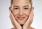 Senior woman, face and skincare smile for beauty touching soft and smooth skin on a studio background. Closeup portrait of a isolated elderly female hands in beautiful facial care smiling for health