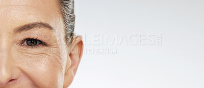 Buy stock photo Half face portrait, skincare and mature woman with beauty treatment standing in studio with mockup space. Lady with natural healthy skin and eye wrinkles with anti aging, hygiene product and selfcare