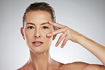 Face, beauty and eyes with a mature woman taking care of her eye or skin in studio on a gray background. Skincare, cosmetics and antiagine with an attractive female posing for wellness and vitality