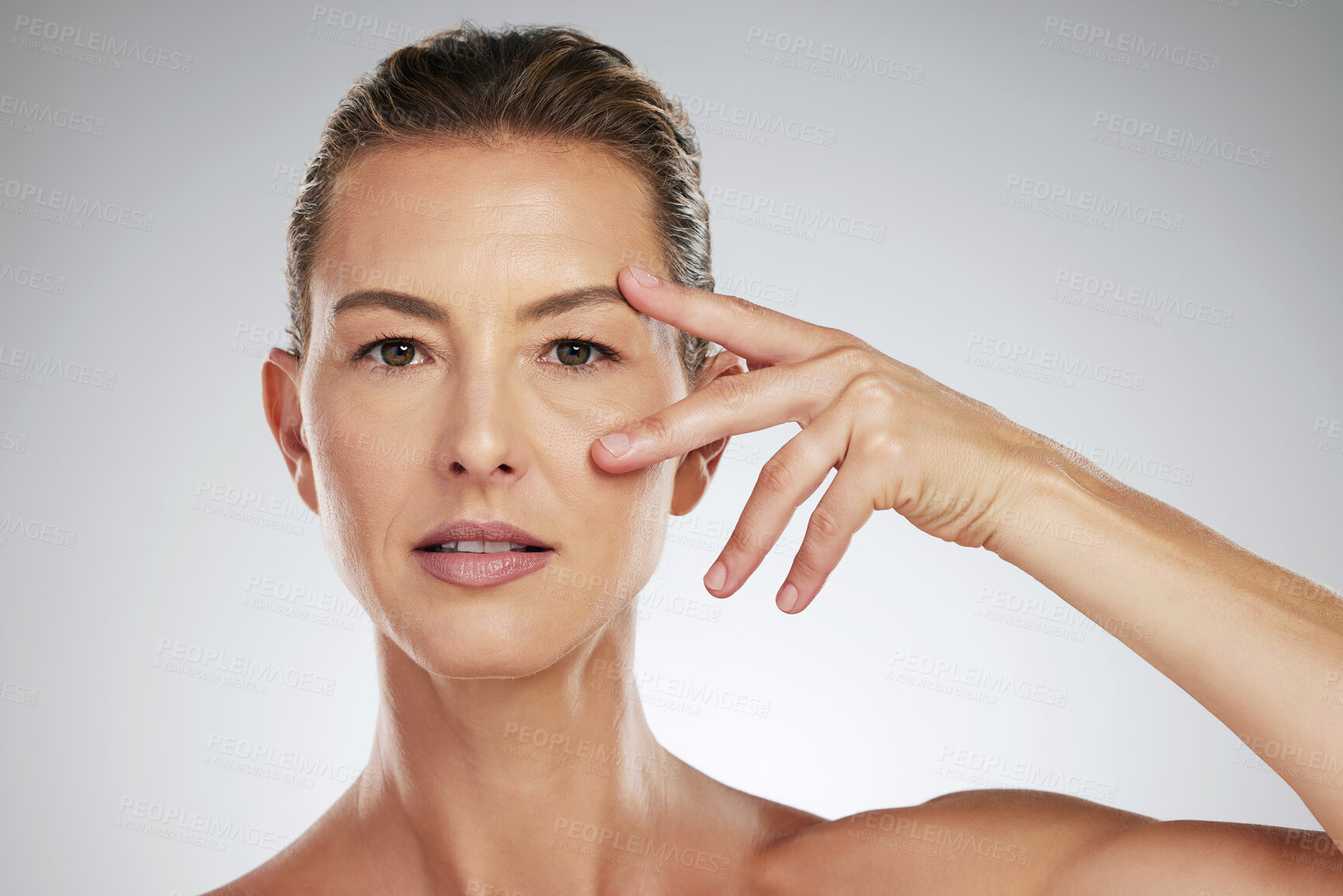 Buy stock photo Face, beauty and eyes with a mature woman taking care of her eye or skin in studio on a gray background. Skincare, cosmetics and antiaging with an attractive female posing for wellness and vitality