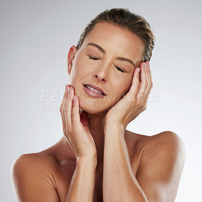 Buy stock photo Face, beauty and skincare with a woman touching her glowing, soft or smooth skin in studio on a gray background. Health, body and care with a mature female putting her hands on her head for wellness