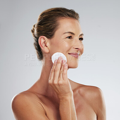 Buy stock photo Mature woman, skincare and facial cotton on a gray studio background. Health, wellness and female model cleaning face and remove makeup, cosmetics or exfoliation for skin anti aging beauty treatment.