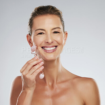 Buy stock photo Jade roller, facial skincare and mature woman with luxury face massage against grey mockup studio background. Happy, healthy and smile for elderly model with dermatology product for skin wellness