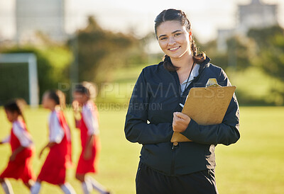 Buy stock photo Soccer field, woman coach with and girl team training on grass in background. Sports, youth development and teamwork, a happy young female volunteer coaching football team with clipboard from Brazil.