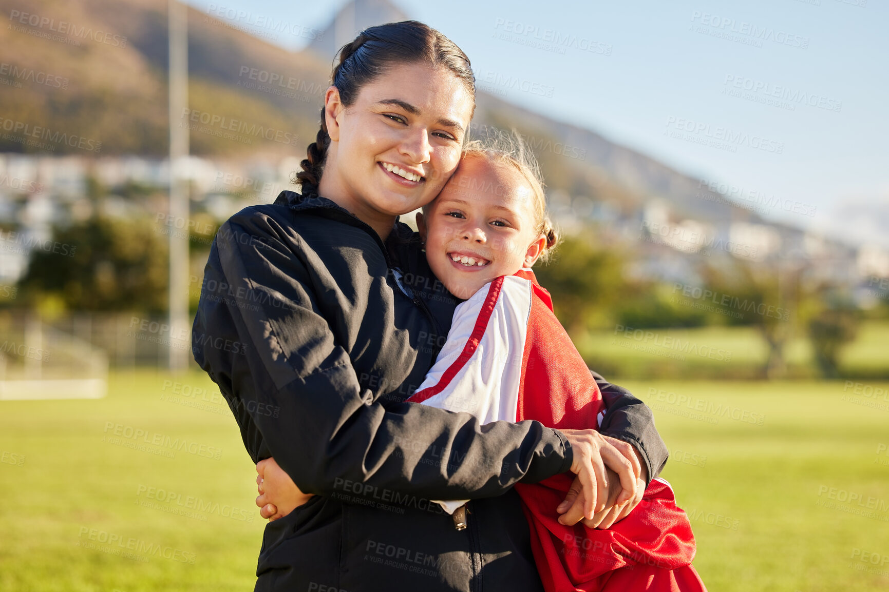 Buy stock photo Football coach, child and hug during sports training on outdoor field for soccer while showing support and motivation for match. Portrait of girl kid or junior player and her woman trainer in russia