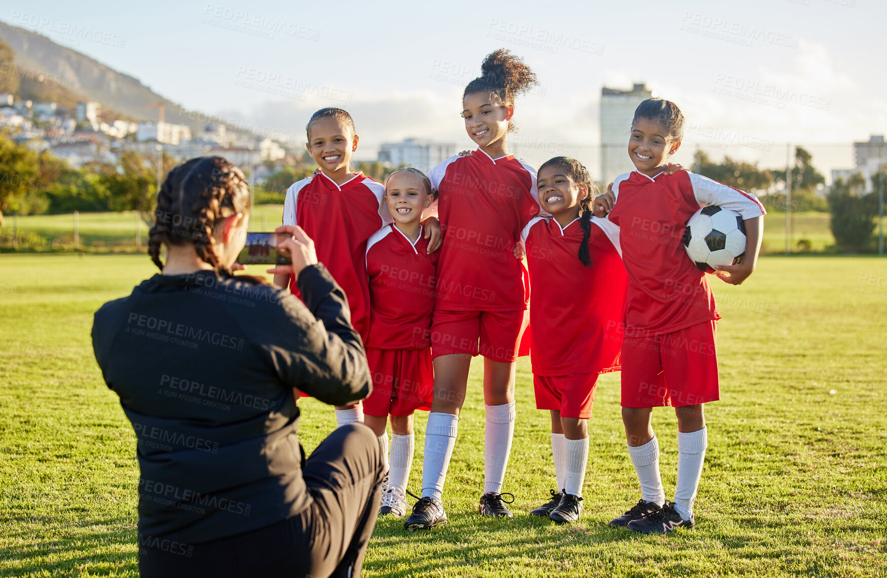 Buy stock photo Soccer, photograph and sports coach with a girl team posing for a picture outdoor on a football field for fitness or training. Exercise, teamwork and picture with athlete kids or friends outside