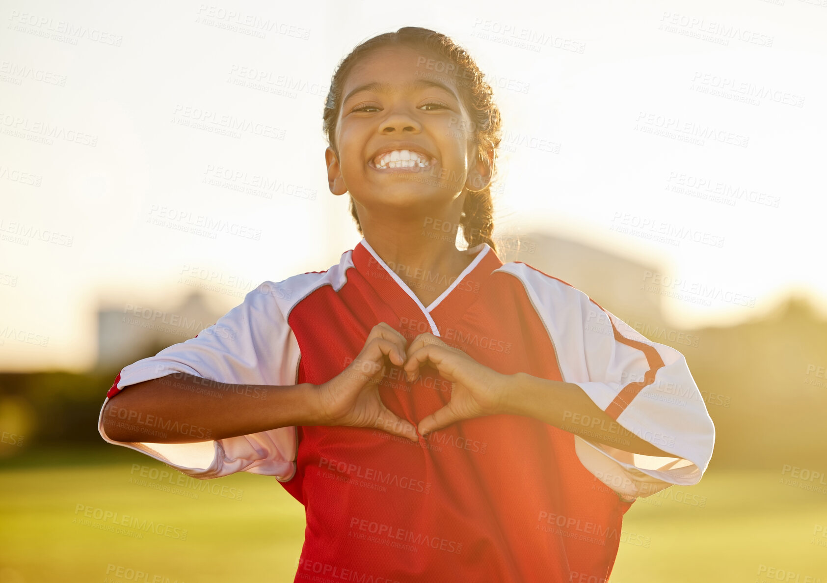 Buy stock photo Girl is happy after football, shows love with a heart hand and smiling at support. Portrait of young athlete celebrate team sports win in gear on the field, excited about exercise and fitness.