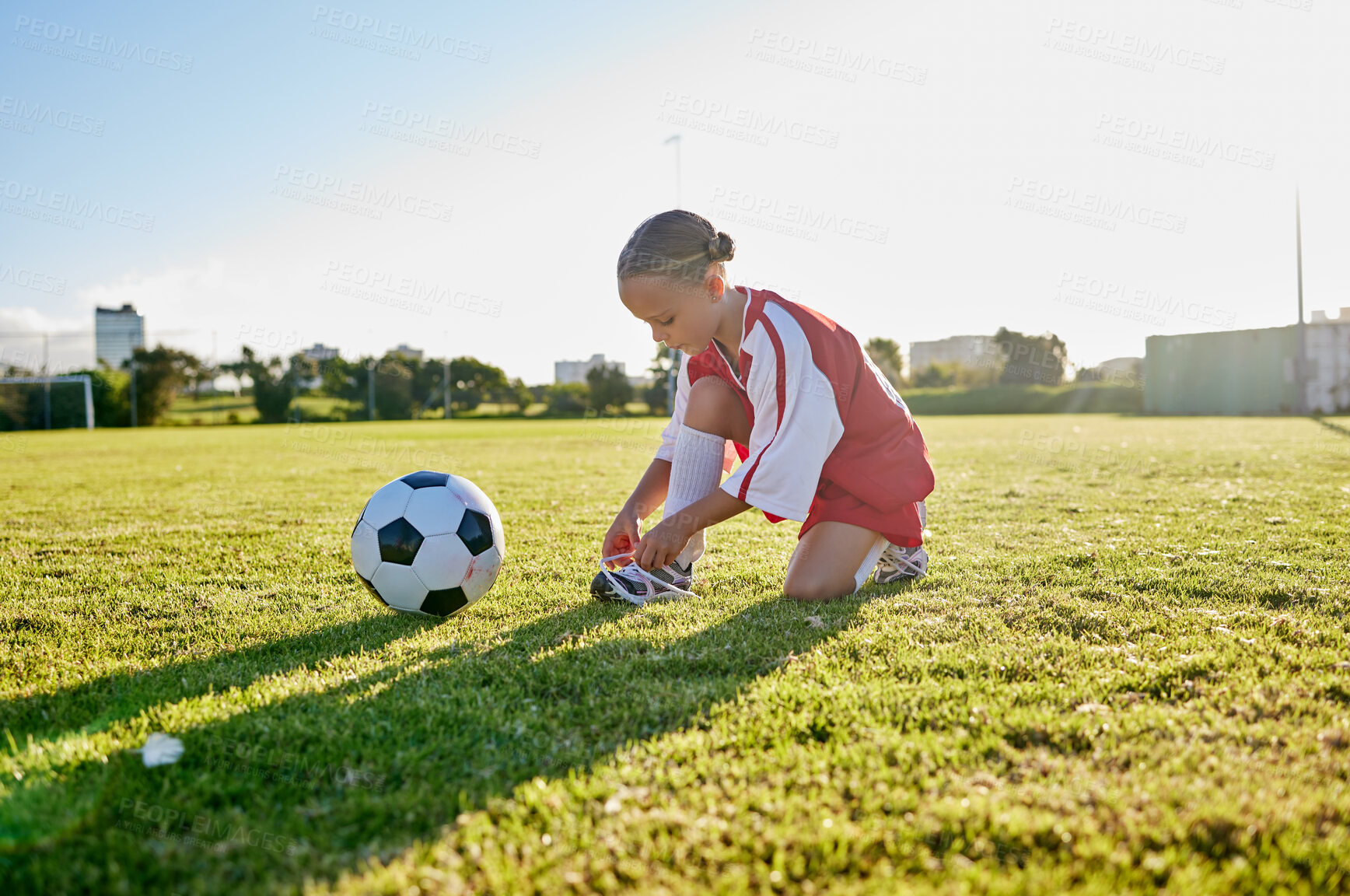 Buy stock photo Soccer, training and tie shoes with girl in sports workout for motivation, health and wellness. Exercise, growth and goals development with young child in football field for games, vision and fitness