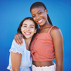 Black women, friends and hug with happy smile on a blue studio background. Portrait, diversity and lesbian couple in love embrace, care and support posing, bonding and spending quality time together.