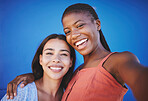 Women, smile and happy for selfie against blue background in diversity while embrace. Friends, face and beauty hug in portrait while show happiness, solidarity and connection against studio backdrop