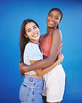 Diversity, friends and women hug with happy smile and woman friendship. Portrait of people smiling embracing love, happiness and female empowerment support in a studio with a blue background