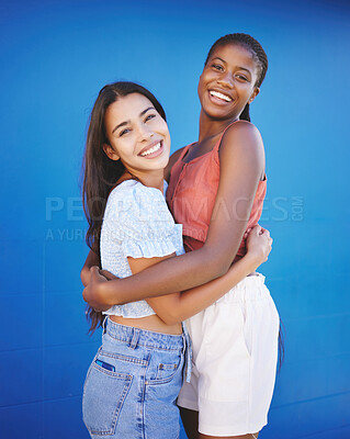 Buy stock photo Diversity, friends and women hug with happy smile and woman friendship. Portrait of people smiling embracing love, happiness and female empowerment support in a studio with a blue background